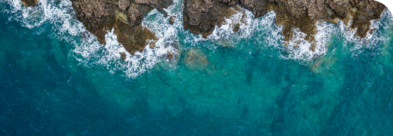 overhead shot of the ocean and a rocky area on the coast