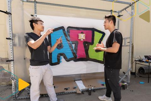 Gerry Chen, Ph.D. candidate in Robotics, and Michael Qian, B.S. Computer Science, '22, with a finished artwork painted by the GTGraffiti robot.